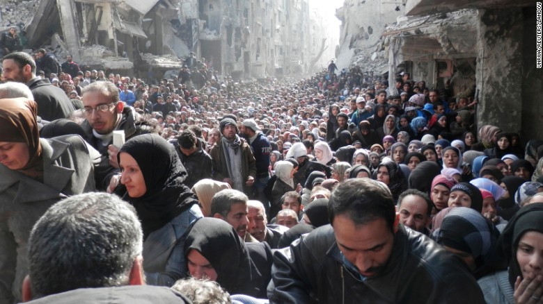 A large crowd of displaced Syrian residents wait for food aid in al-Yarmouk camp